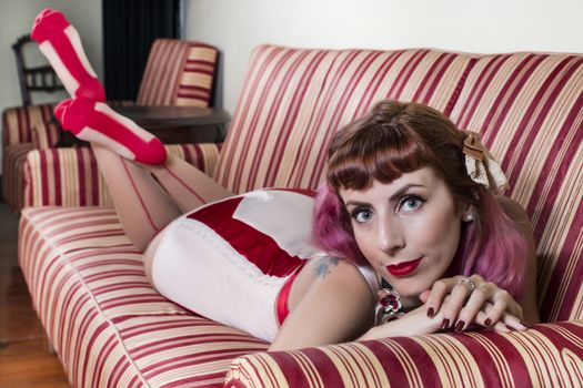 Girl with red vintage lingerie with a striped sofa in the living room.