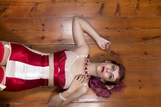 Girl with red vintage lingerie on a wooden floor.