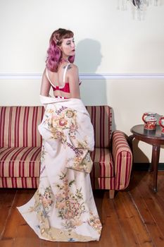 Girl with red vintage lingerie with a striped sofa in the living room.