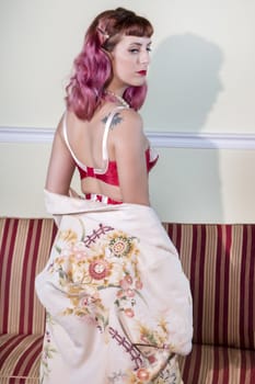 Girl with red vintage lingerie with a striped sofa in the living room.