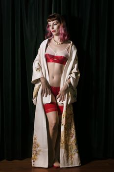 Girl with red vintage lingerie and kimono next to velvet curtains.