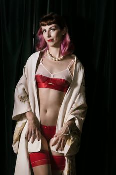 Girl with red vintage lingerie and kimono next to velvet curtains.