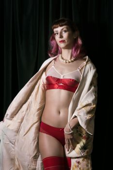 Girl with red vintage lingerie and kimono next to velvet curtains.