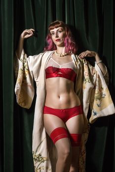 Girl with red vintage lingerie and kimono next to velvet curtains.