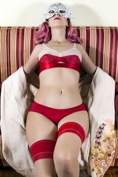 Girl with red vintage lingerie with a striped sofa in the living room.