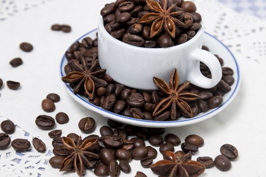 Composition of a cup full of coffee beans on table.