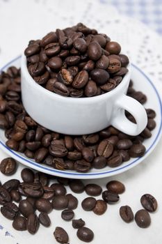 Composition of a cup full of coffee beans on table.
