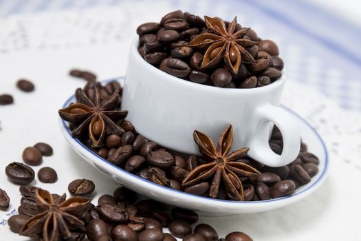 Composition of a cup full of coffee beans on table.