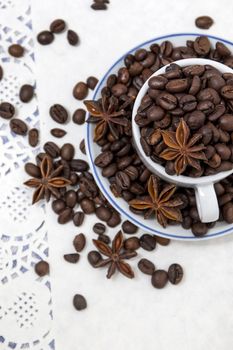 Composition of a cup full of coffee beans on table.