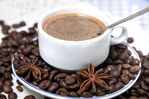 Composition of a coffee cup with spreaded beans and star anise.