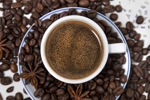 Composition of a coffee cup with spreaded beans and star anise.