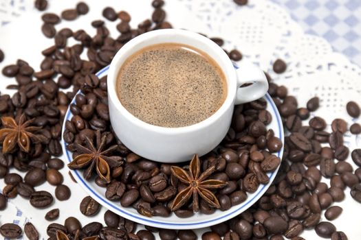 Composition of a coffee cup with spreaded beans and star anise.