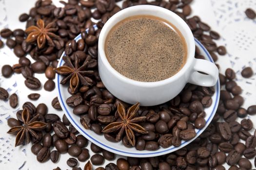 Composition of a coffee cup with spreaded beans and star anise.