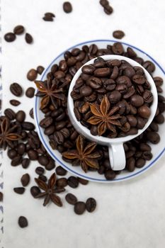 Composition of a cup full of coffee beans on table.