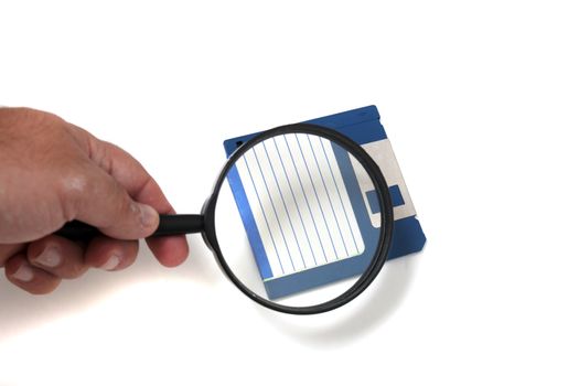 hand with magnifying glass inspecting on floppy disk concept.