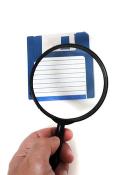hand with magnifying glass inspecting on floppy disk concept.