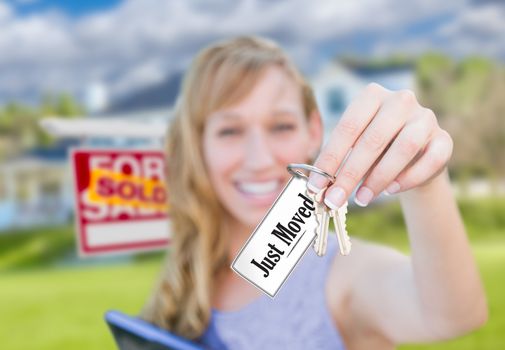 Woman Holding New House Keys with Just Moved Card In Front of Sold Real Estate Sign and Home.