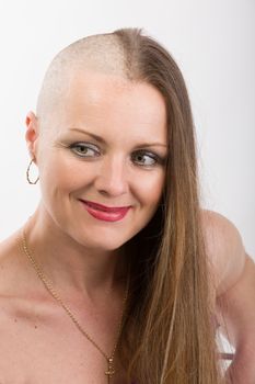 Portrait of smiling beautiful middle age woman patient with cancer with partially shaved head, hope in healing. She lost her hair