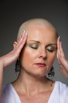 Portrait of beautiful middle age woman sad patient with cancer with shaved head without hair, hope in healing. Woman holding her head