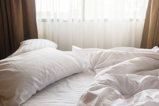 white pillow and blanket with wrinkle messy on bed in bedroom, messy from sleeping in a long night winter.