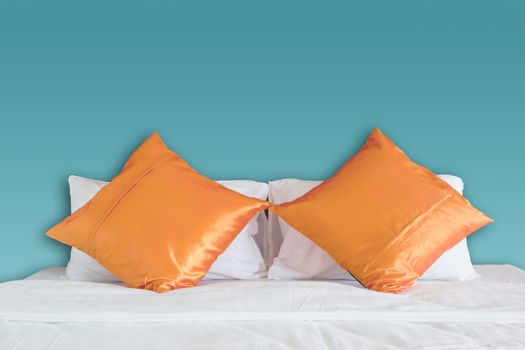 blue wall and orange pillow on white bed