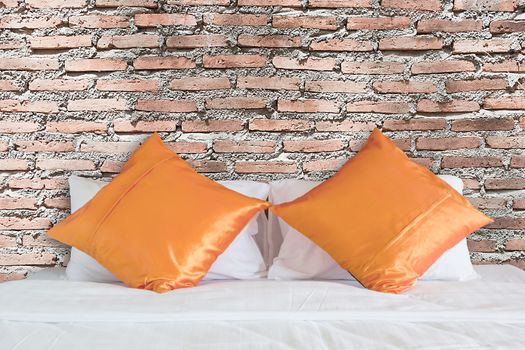 vintage red brick wall and orange pillow on white bed