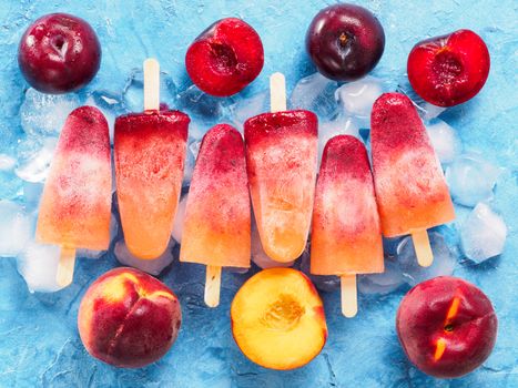 top view of plum and peach popsicle on blue background. Fruit popsicles ice cream with fresh plums and peach.