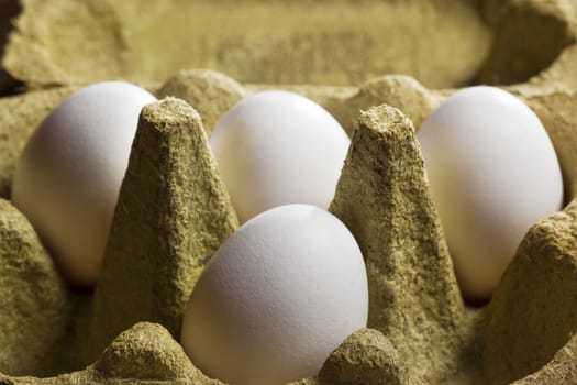 Four white organic eggs in a box consisting of 50 percent grass fibers and is fully recyclable