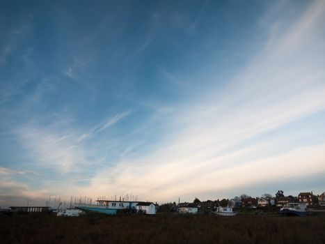 row of beach front marina houses with big open blue sky space; west mersea, essex, england, uk