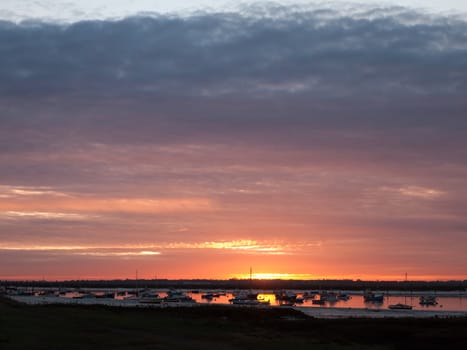 sun set sky dramatic clouds sea front beach harbor marina boats moored landscape; west mersea, essex, england, uk