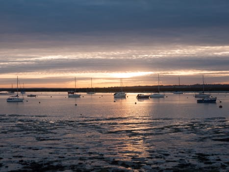 sun set sky dramatic clouds sea front beach harbor marina boats moored landscape; west mersea, essex, england, uk