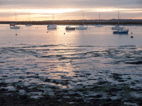 sun set sky dramatic clouds sea front beach harbor marina boats moored landscape; west mersea, essex, england, uk