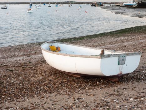 small white private boat parked moored on beach front bay ; west mersea, essex, england, uk