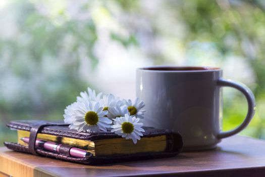 Mug, daisies, Notepad, glasses. The concept of a Sunny summer morning.