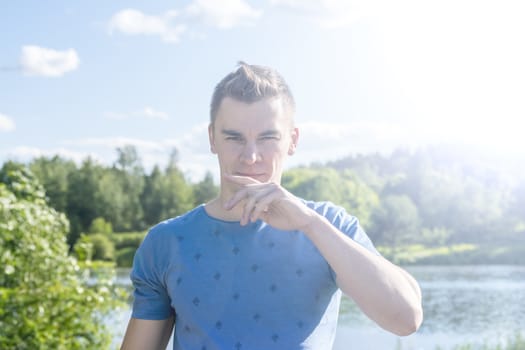 The young man in the background of the pond. Summer. Portrait.