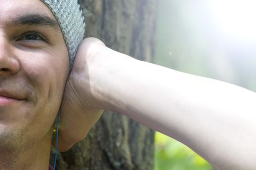 A young man sits under a tree and listens to music