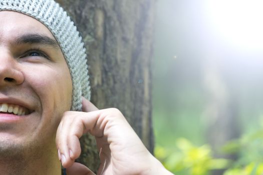 A young man sits under a tree and listens to music