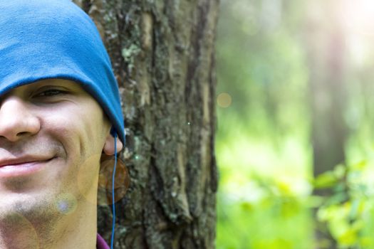 A young man sits under a tree and listens to music