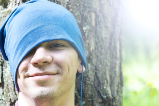 A young man sits under a tree and listens to music