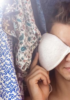 A young man hiding in the closet among women's clothing. Lover in the closet.