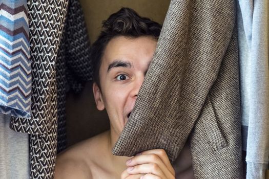 a young man hiding in the closet women's clothing