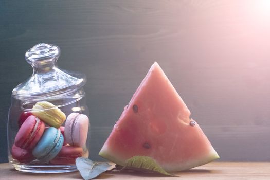 Macaroon, watermelon on a wooden table. The concept of home comfort and warmth.