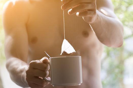 The young man brewing the tea bag. Morning awakening.