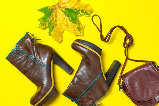 Female shoes, bag, autumn leaves on a yellow background. The concept of autumn.
