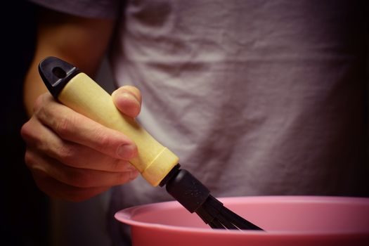 The man whips the batter with a whisk. Cooking, baking, meal.