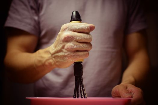The man whips the batter with a whisk. Cooking, baking, meal.