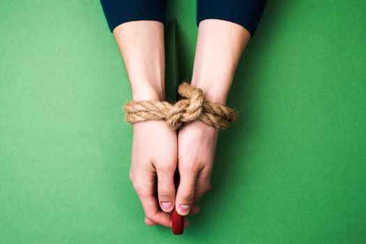 The man with bound hands and knife on green background