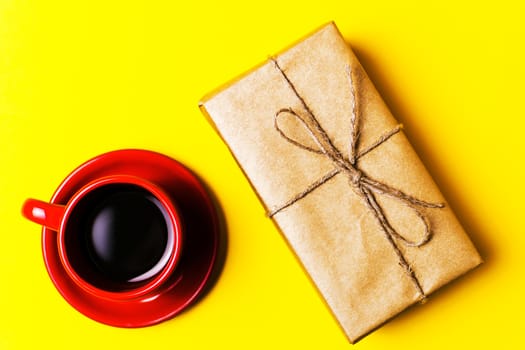 Red Cup with coffee and gift on yellow background