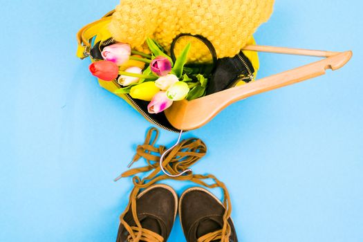 Women's bag with clothes and shoes on a colored background