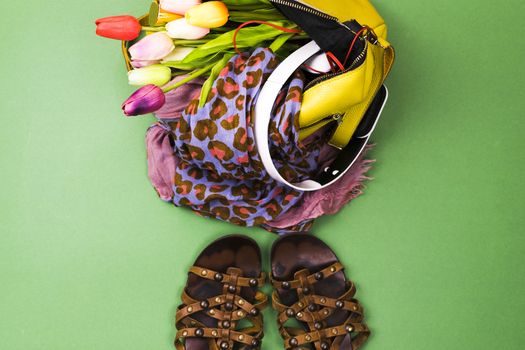 Women's bag with clothes and shoes on a colored background
